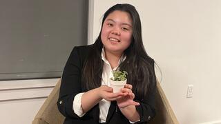 Female wearing suit and holding a small plant