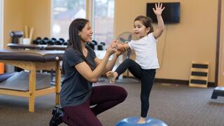 Physical therapist working with child to help her exercise