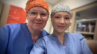 Erica Cabrera, AAS ’26, and Alexandra Gooding, AAS ’25, smile in surgical caps and scrubs