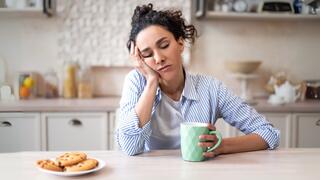 A woman sleeps propped up on her hand at a kitchen table