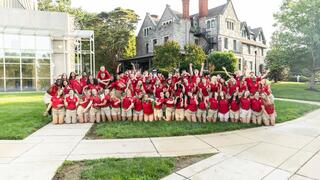 Saint Joseph's University orientation leaders in red polos and khaki shorts pose in front of the Chapel of Saint Joseph.