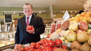 John Stanton in a grocery store holding a tomato