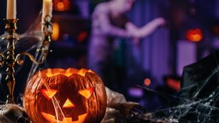 A pumpkin sits on a table with cobwebs 