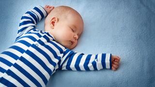 A baby asleep on a blue sheet