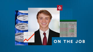 A man in a suit and tie smiling next to soda cans