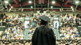 Student speaker in regalia facing audience