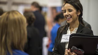 A young student smiles and chats with a potential employer at the Career Fair.
