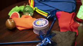 Sensory-friendly toys, including a blue pinwheel, a mini-football and a clear bouncy ball, on a brown table. Inclu