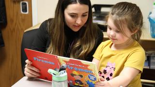 Teacher reading a book with a young student