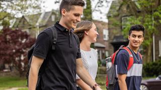 Closeup of three students walking through campus talking to one another