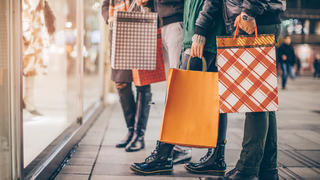 People window shopping while holding holiday bags in their hands.