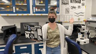 Student holds a laptop in Saint Joseph's biology lab.