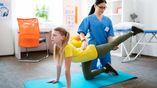 Physical therapist helping a young client stretch