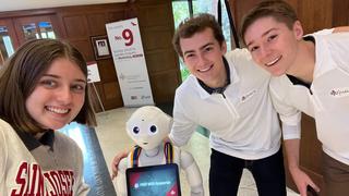 Three students pose with Pepper the robot