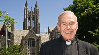 Joseph J. Feeney, S.J., standing outside of Barbelin Hall Hawk Hill campus smiling