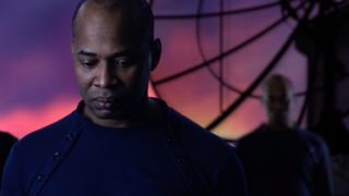 A man stares into the distance in front of a purple sky.
