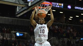 Former SJU basketball player throwing basketball into net on court