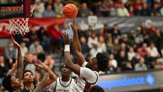 Saint Joseph's Christ Essandoko throwing basketball into net on court