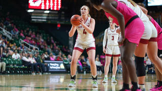 Female SJU basketball player throwing ball into net on court