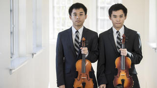 twin brothers wearing suits and holding a violin
