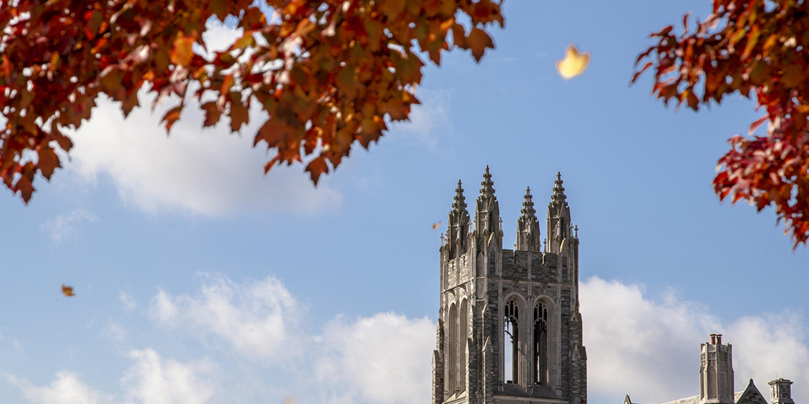 The tall gothic spires of Barbelin Hall framed by trees with red fall leaves