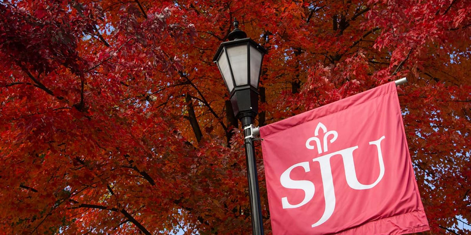 A banner hung from a lamp post with the SJU logo