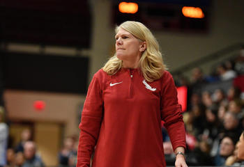 Saint Joseph's coach Cindy Griffin standing on basketball court with audience behind on bleachers