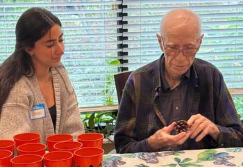 Jessica Haddad, BS ’26, sits with Anthony Berret, S.J., on a Halloween-themed plant project.