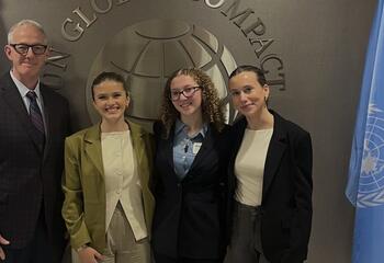 A professor and three students standing in front of the United Nations logo