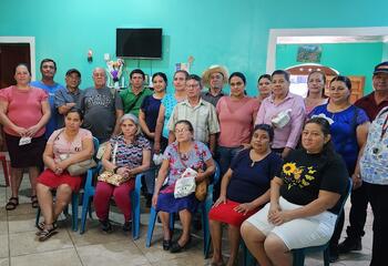 A group of Salvadoran adults look at the camera in front of a bright blue wall 