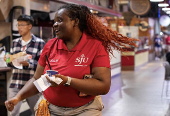 Kaia Grant wearing red orientation shirt dancing in Philadelphia Reading Terminal Market