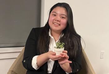 Female wearing suit and holding a small plant