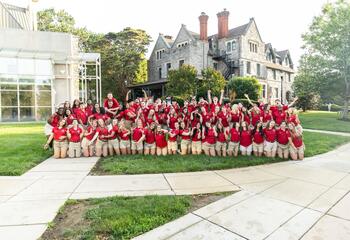 Saint Joseph's University orientation leaders in red polos and khaki shorts pose in front of the Chapel of Saint Joseph.