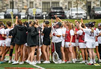 Saint Joseph's women's lacrosse team in field in team huddle