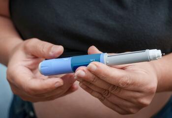 Two hands holding a GLP-1 injector