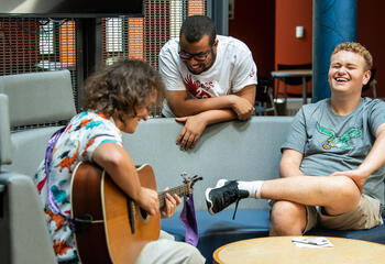 Students in Merion Hall playing guitar and laughing