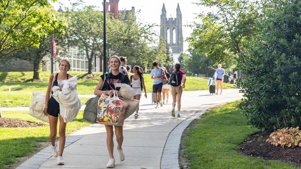 Students walking with bags across campus with Barbelin Hall in the background