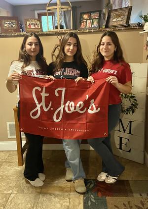 Oliveira sisters in Saint Joseph's shirts holding a St. Joe's flag