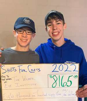 Two male teenagers holding a large check for $8,165.