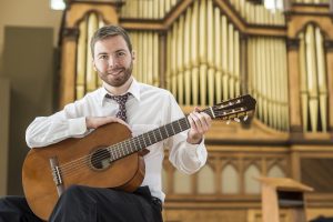 John Bradley holding a guitar in the chapel