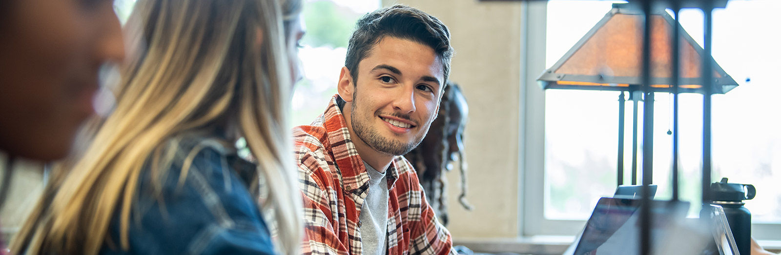 student talking to a classmate in the library