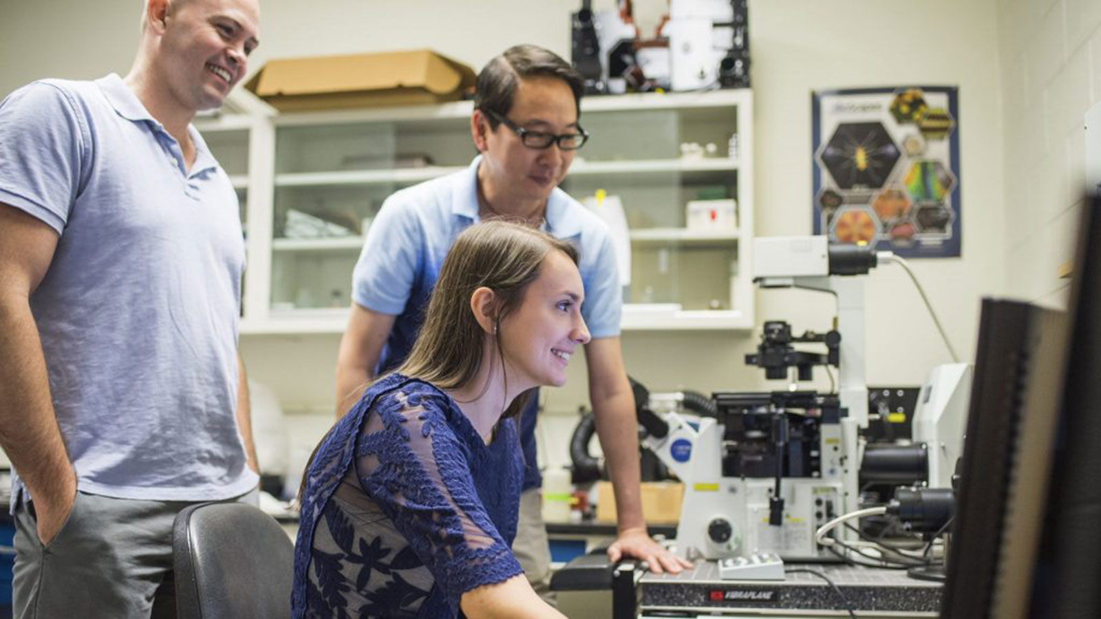 biology student working with two professors in laboratory