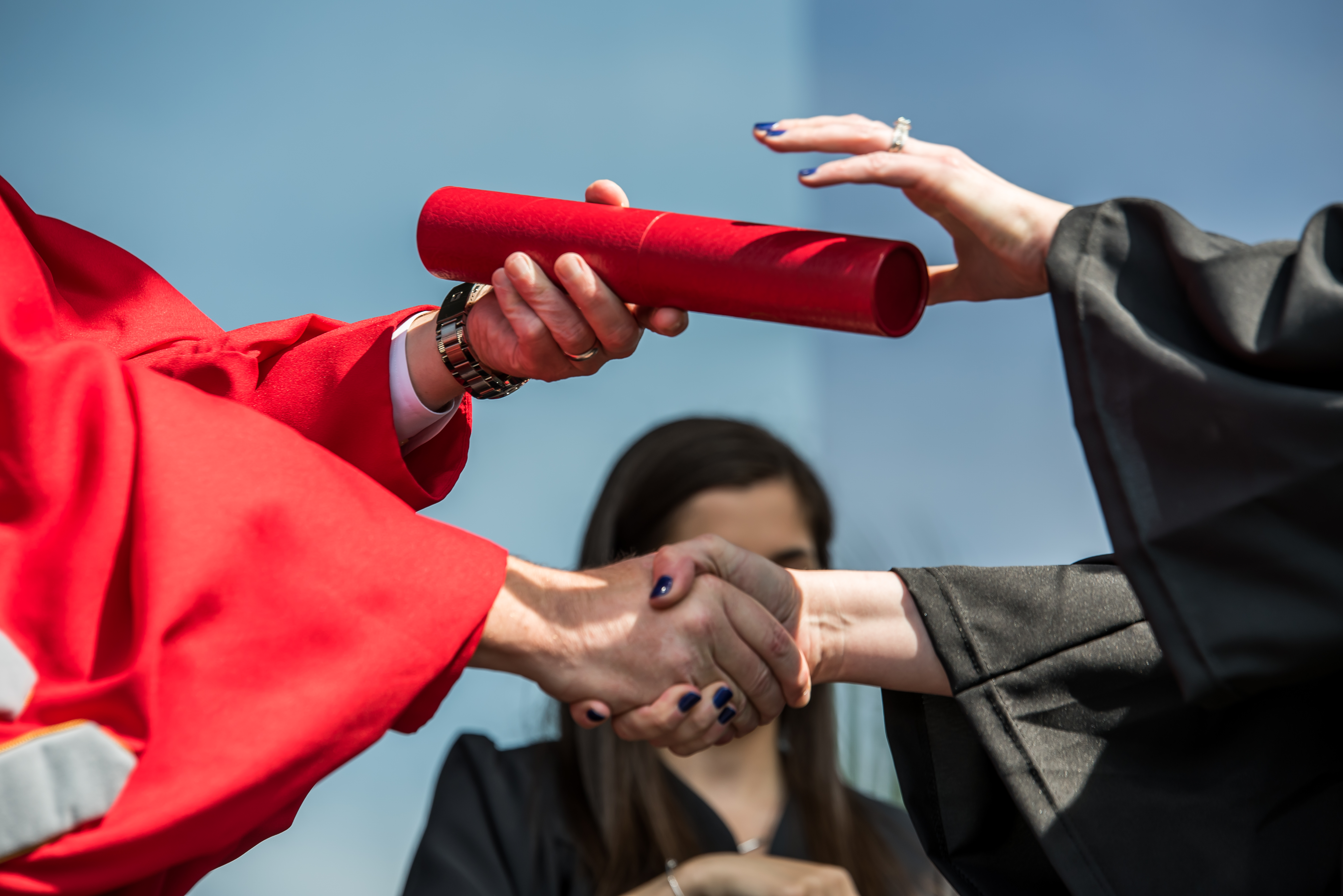 hands exchanging a diploma on a commencement stage