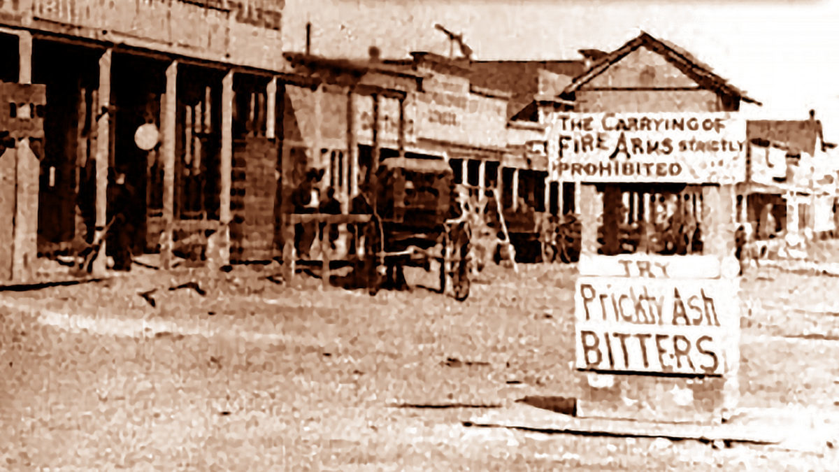 An old photo of Dodge City and a sign that reads "The carrying of firearms strictly prohibited."