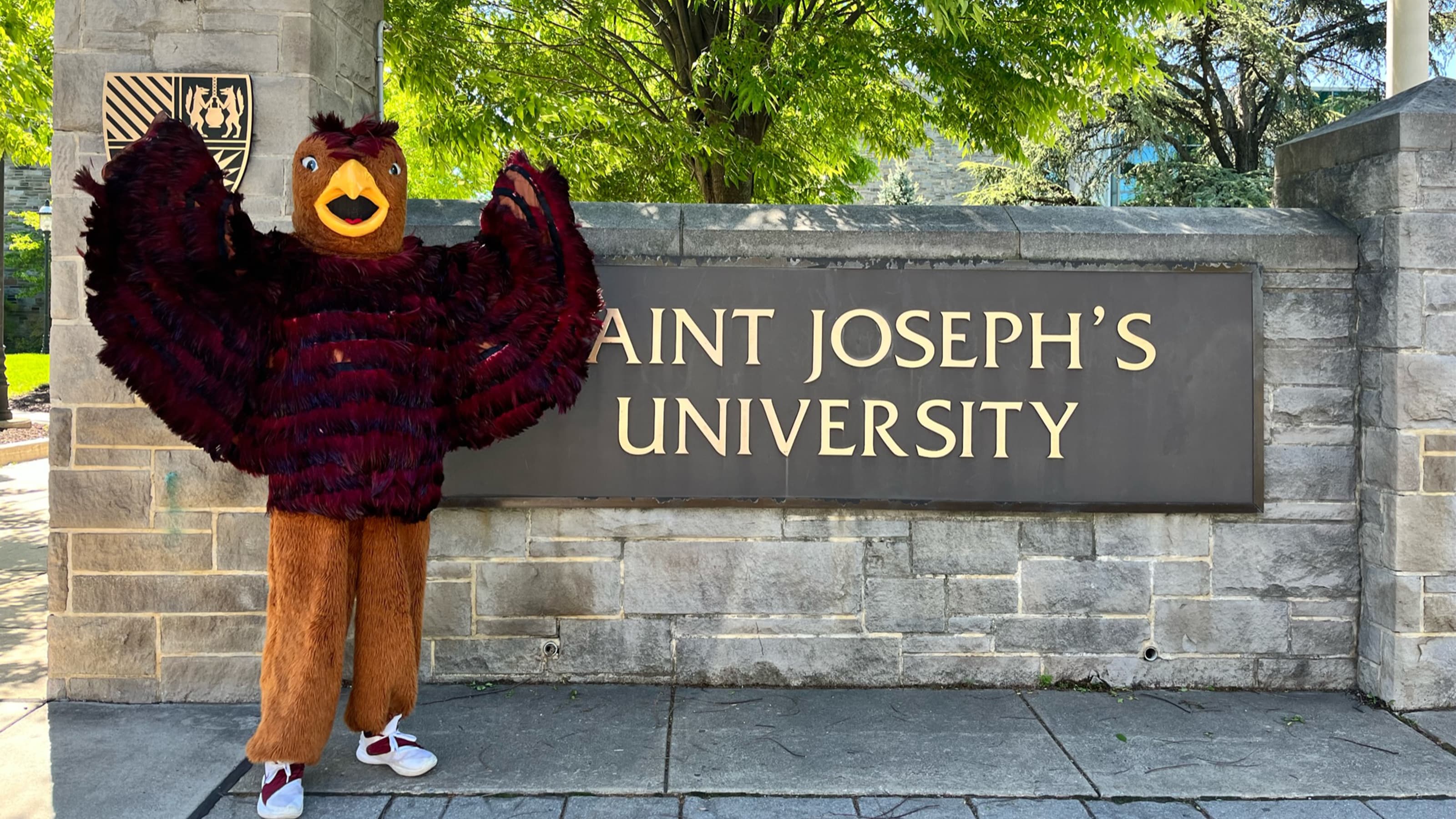 Hawk mascot in front of Saint Joseph's University sign