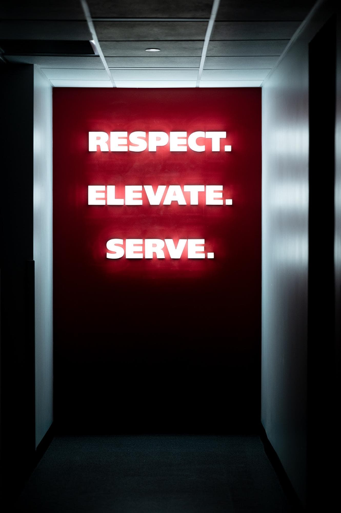 A lit up sign in the men's locker room that says "Respect. Elevate. Serve." 