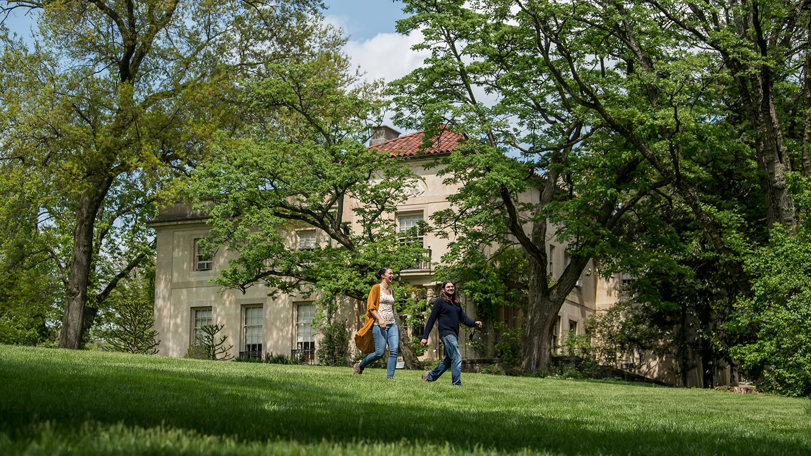 Two students walking in front of the Barnes Arboretum at Saint Joseph’s University