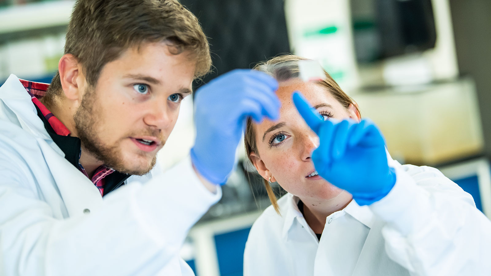 Two students inspecting material in a lab