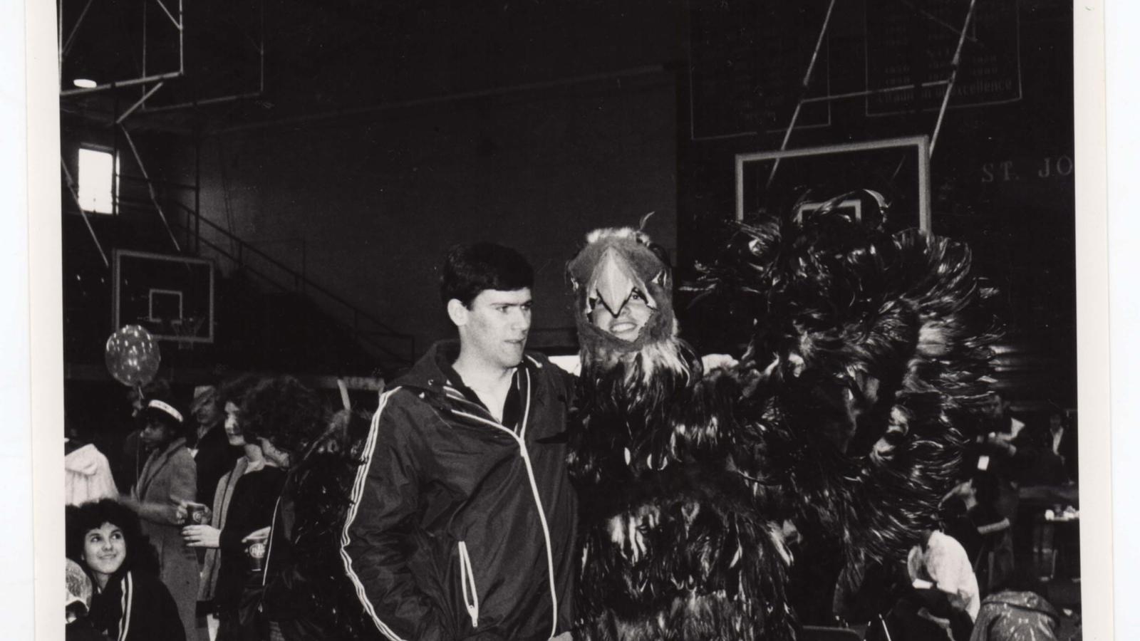 A black and while photo of a young man with the first hawk mascot
