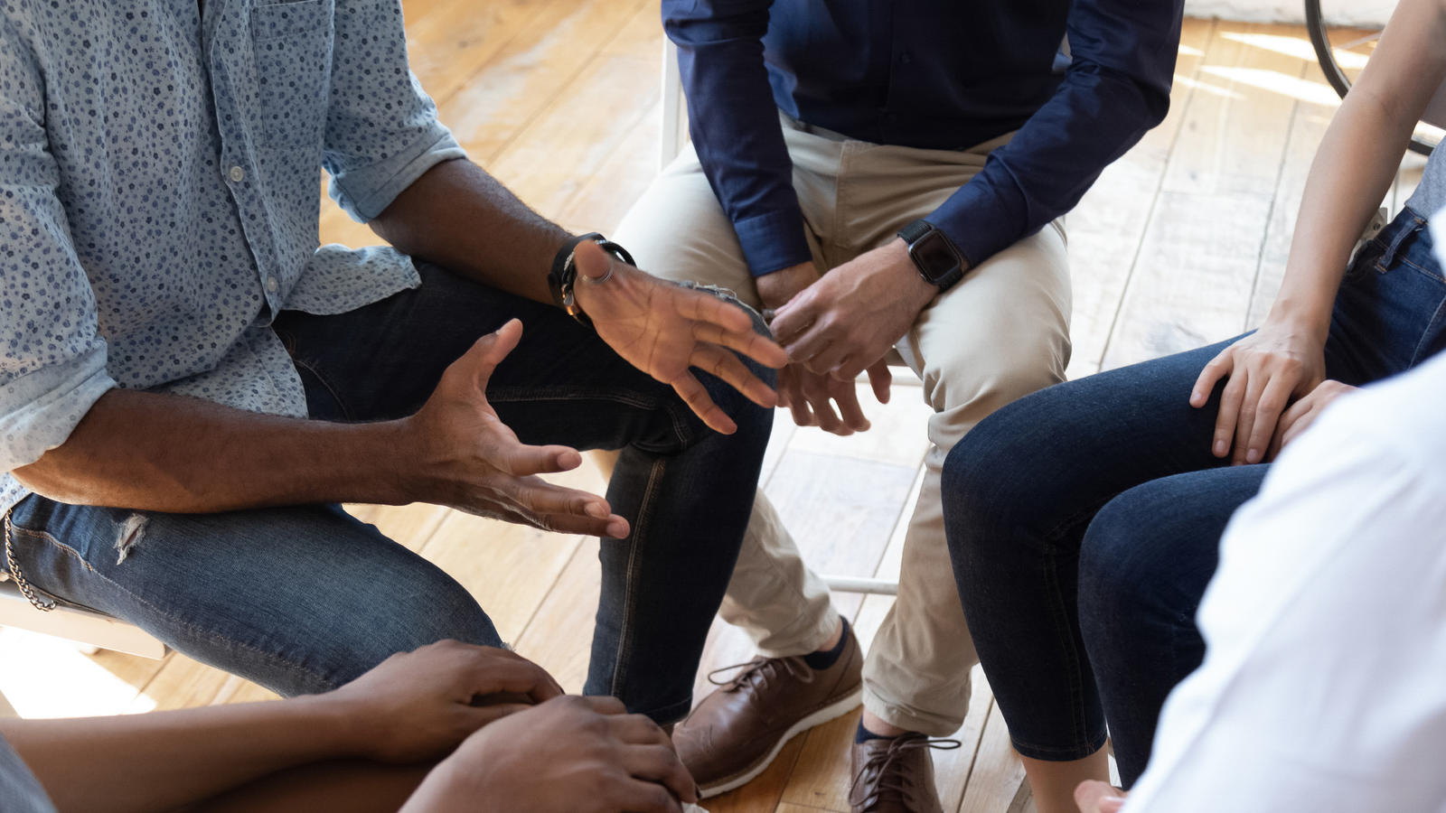 A closeup of hands in a circle, perhaps in a recovery group meeting